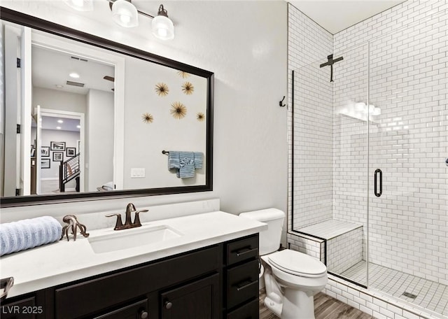 bathroom with vanity, wood finished floors, a shower stall, and toilet