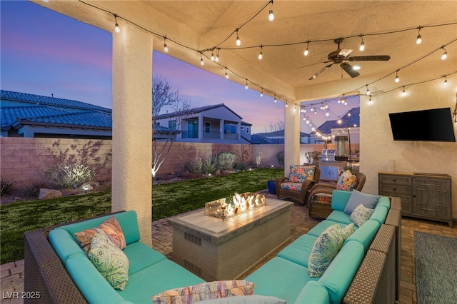 view of patio featuring a ceiling fan, an outdoor living space with a fire pit, and a fenced backyard