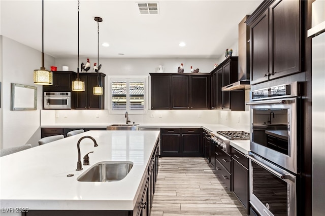 kitchen featuring appliances with stainless steel finishes, visible vents, light countertops, and a sink