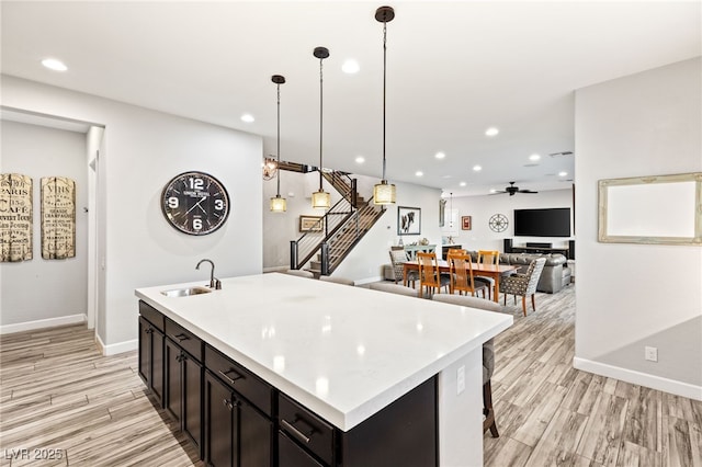 kitchen with light countertops, light wood finished floors, a sink, and recessed lighting