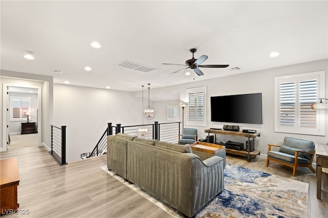 living area featuring recessed lighting, visible vents, light wood-style flooring, and ceiling fan with notable chandelier