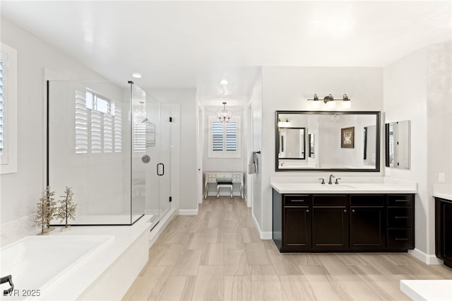 full bath with a stall shower, a garden tub, vanity, and baseboards