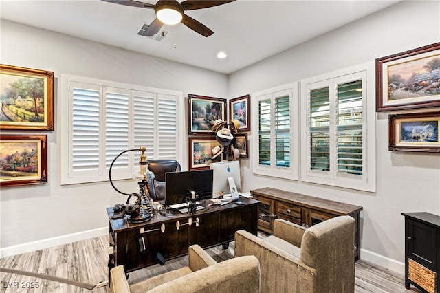 home office with a ceiling fan, wood finished floors, visible vents, and baseboards