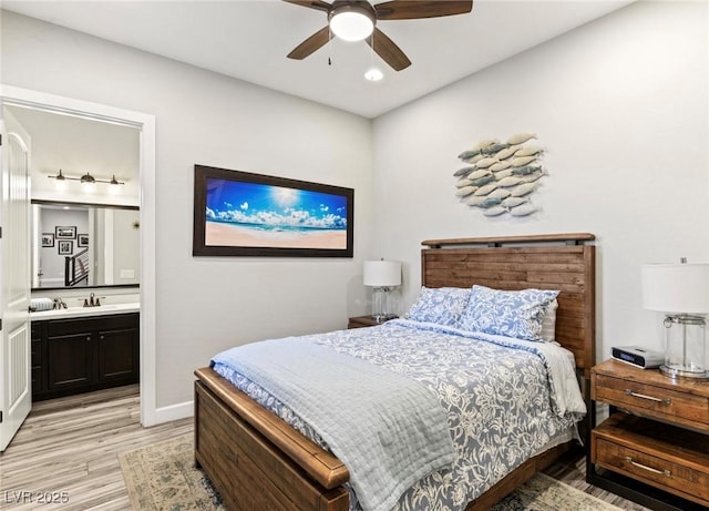 bedroom featuring light wood finished floors, ensuite bath, baseboards, and ceiling fan