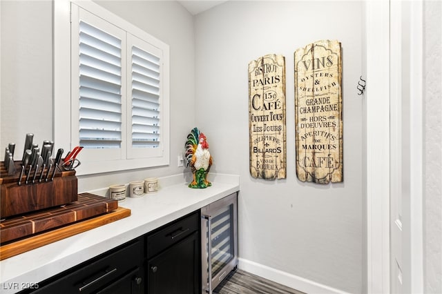 bar featuring wine cooler, wood finished floors, and baseboards