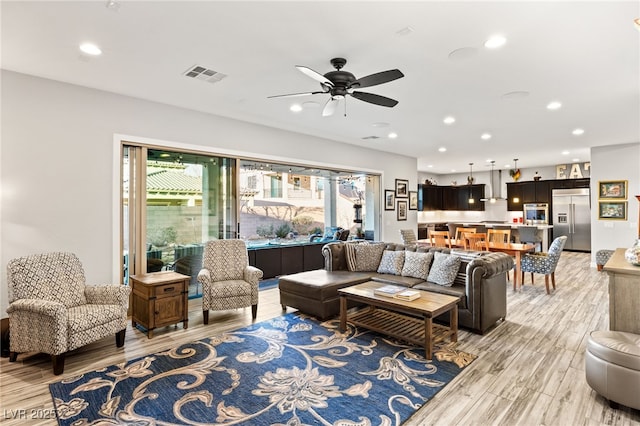 living area featuring a ceiling fan, recessed lighting, visible vents, and light wood finished floors