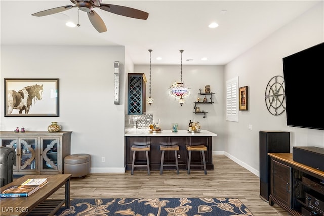 bar featuring baseboards, recessed lighting, wood finished floors, and bar