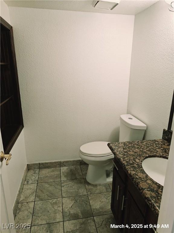 half bathroom with toilet, baseboards, visible vents, and vanity