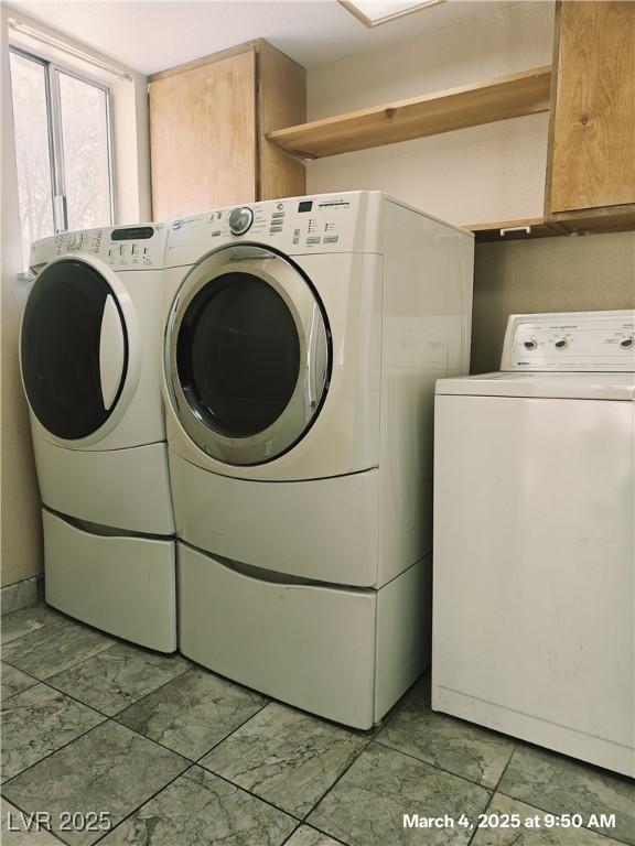 clothes washing area featuring cabinet space and washer and dryer