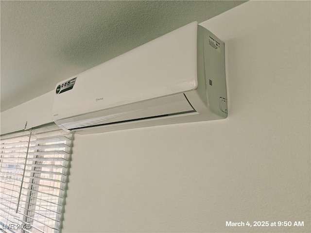 interior details featuring a textured ceiling and an AC wall unit