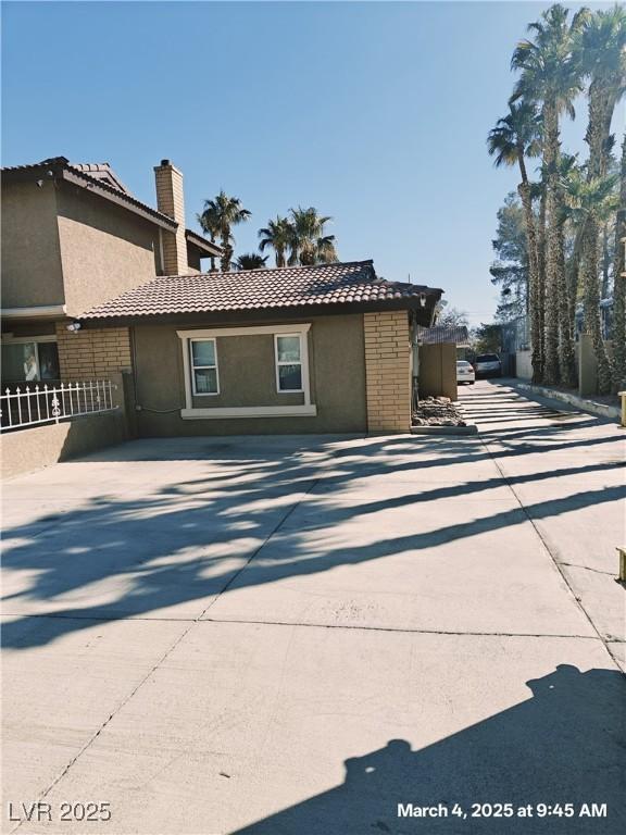 exterior space with a tiled roof, a chimney, and stucco siding