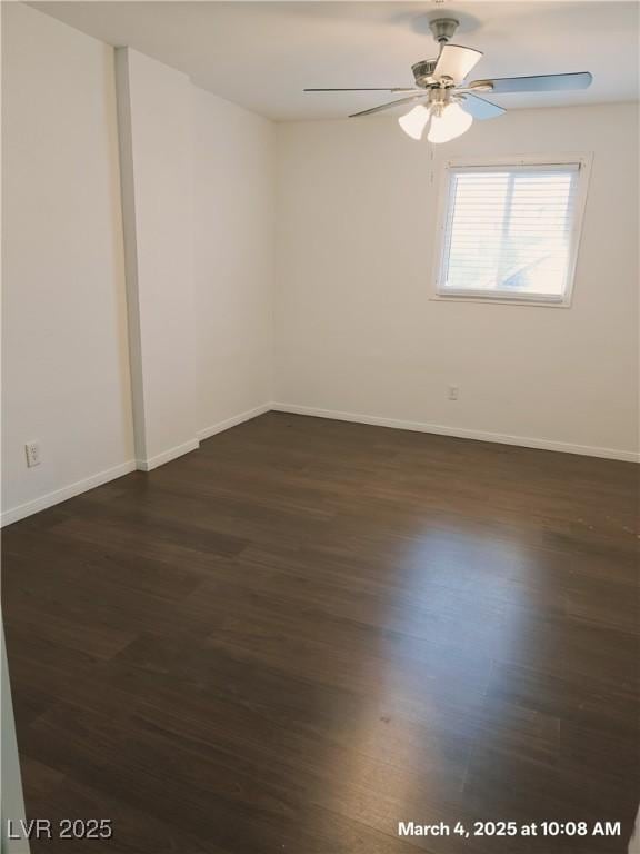 spare room with dark wood-style floors, a ceiling fan, and baseboards