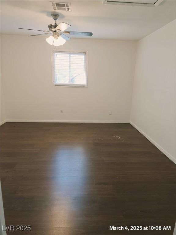 empty room with a ceiling fan, visible vents, dark wood finished floors, and baseboards