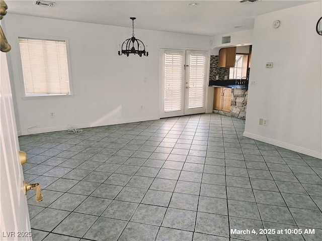 empty room featuring light tile patterned floors, baseboards, a notable chandelier, and french doors