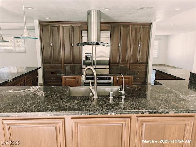 kitchen featuring dark stone counters, a healthy amount of sunlight, visible vents, and a center island