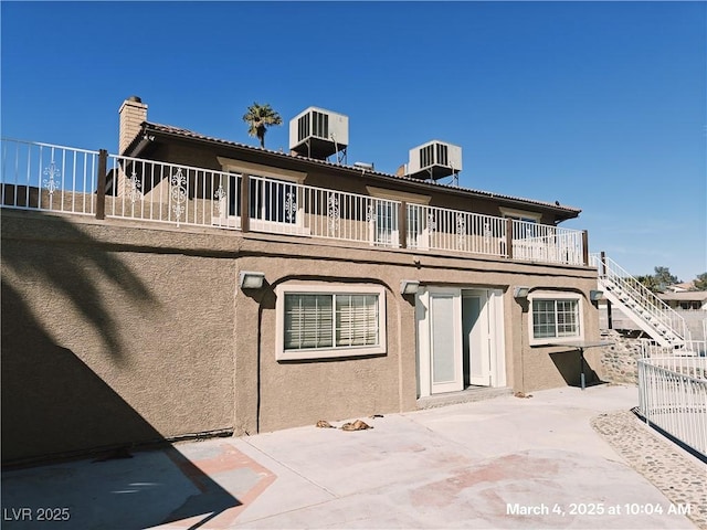 back of property featuring stairs, a patio area, central AC, and stucco siding