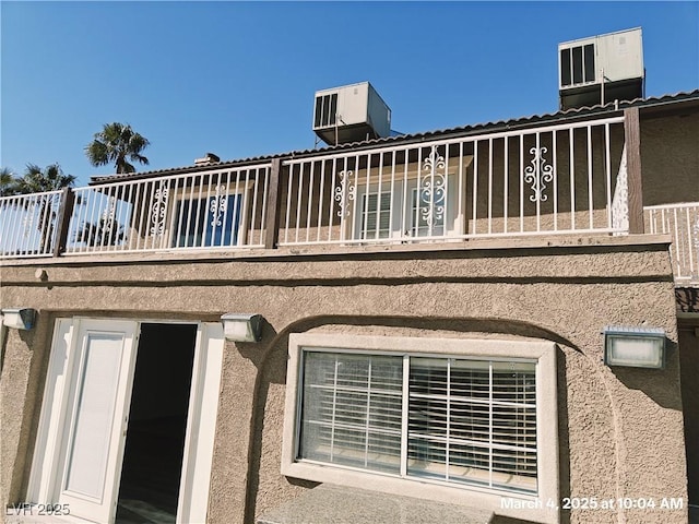 rear view of house with central AC unit and stucco siding