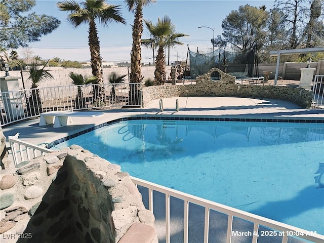 view of swimming pool with a trampoline, fence, and a fenced in pool