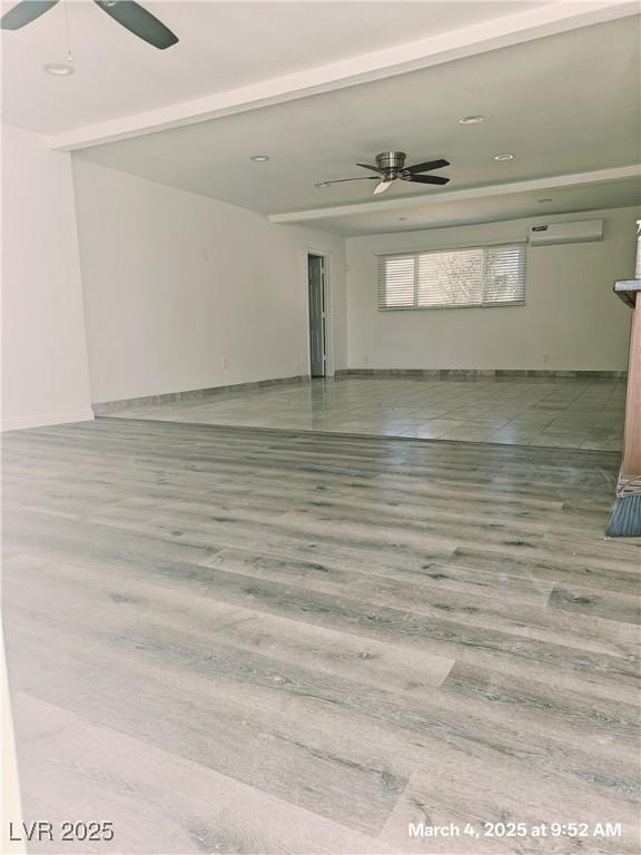 spare room featuring a wall mounted air conditioner, a ceiling fan, and wood finished floors