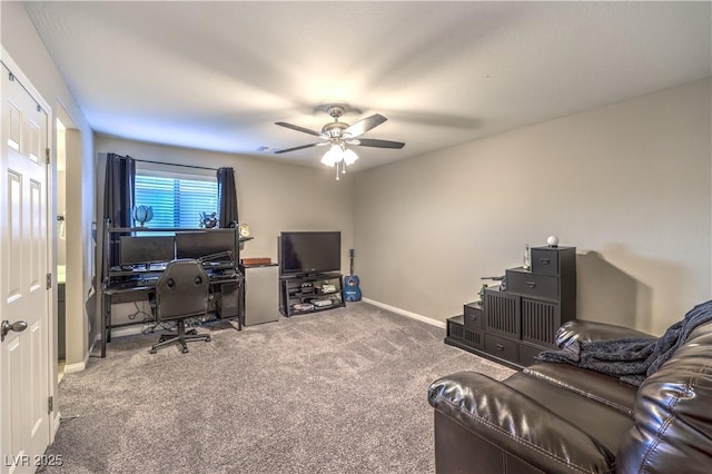 carpeted office space with a ceiling fan and baseboards