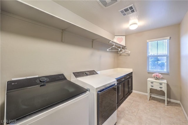 washroom with washer and clothes dryer, light tile patterned floors, visible vents, cabinet space, and baseboards