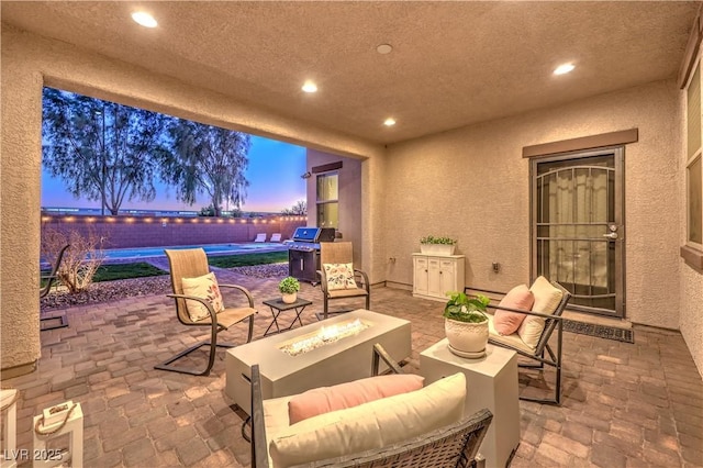 patio terrace at dusk with a pool, an outdoor fire pit, and grilling area