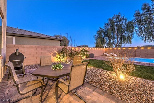 view of patio / terrace with a fenced backyard, a grill, a fenced in pool, and outdoor dining space