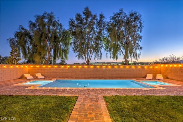 pool at dusk featuring a fenced in pool, a fenced backyard, a yard, and an in ground hot tub