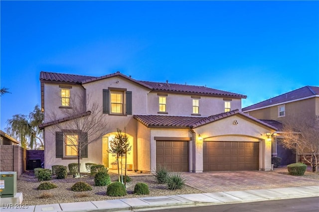 mediterranean / spanish-style house with cooling unit, fence, a tiled roof, decorative driveway, and stucco siding