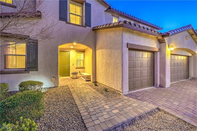 view of front of home with a tile roof, an attached garage, and stucco siding