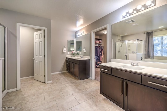 bathroom featuring visible vents, a spacious closet, a stall shower, a sink, and tile patterned flooring