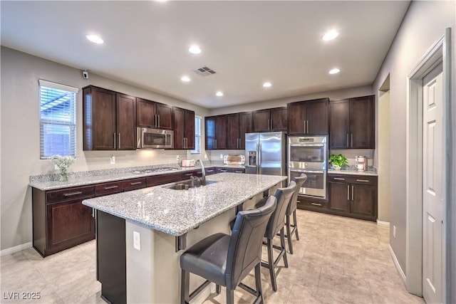 kitchen featuring visible vents, a kitchen bar, appliances with stainless steel finishes, and dark brown cabinets