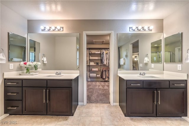 full bath with two vanities, a sink, and a walk in closet