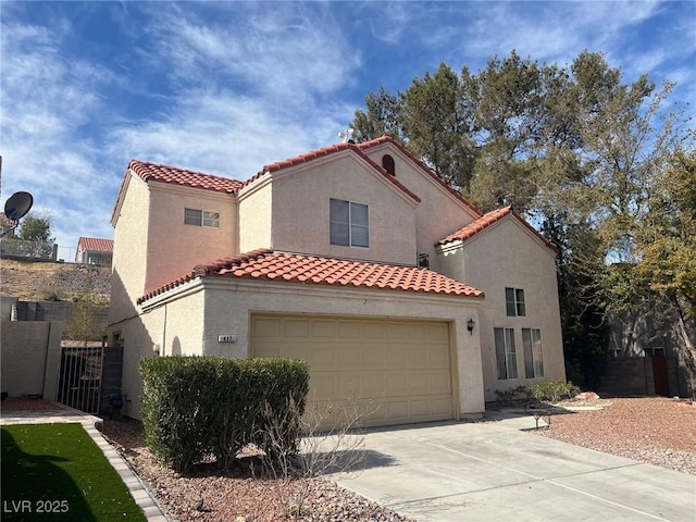 mediterranean / spanish house with fence, concrete driveway, a tiled roof, a gate, and stucco siding