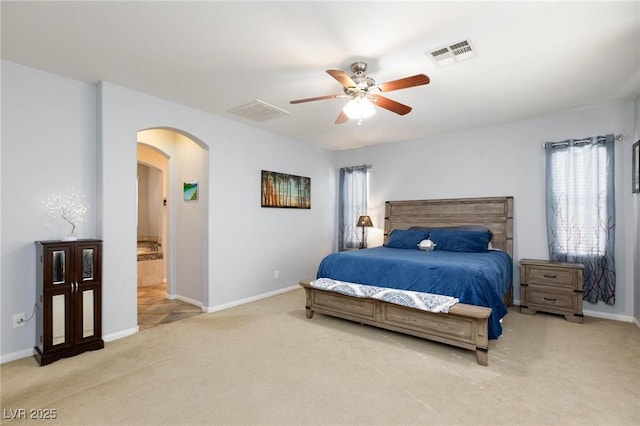 bedroom with light carpet, baseboards, visible vents, and arched walkways