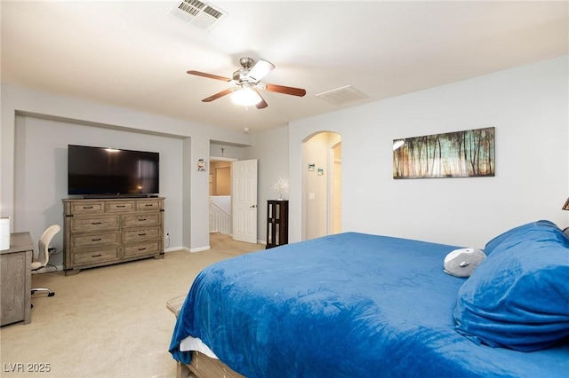 bedroom featuring light carpet, visible vents, arched walkways, and a ceiling fan