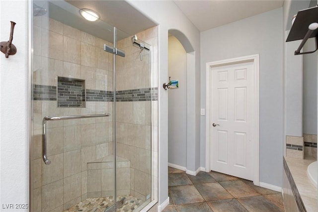 bathroom featuring a shower stall, baseboards, and a bath