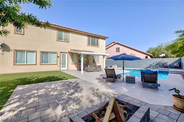 rear view of house with a fenced in pool, a patio, stucco siding, fence, and a tiled roof