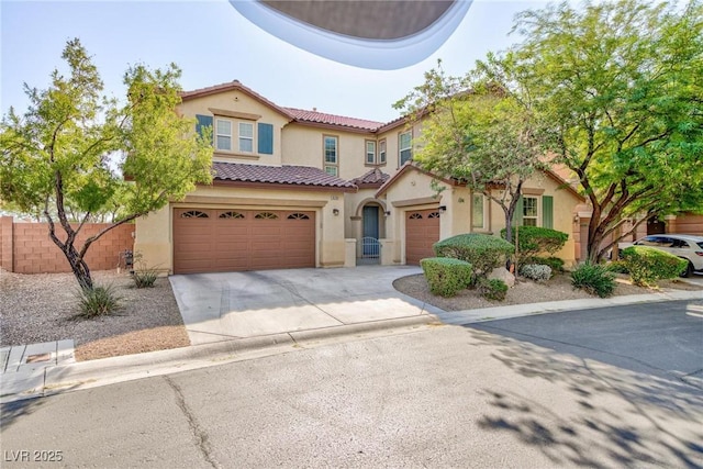 mediterranean / spanish-style house featuring a tile roof, stucco siding, concrete driveway, an attached garage, and fence