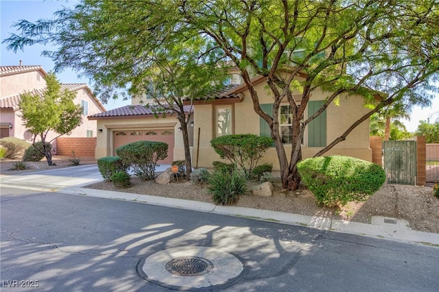 view of front of home with driveway, a garage, a tile roof, fence, and stucco siding