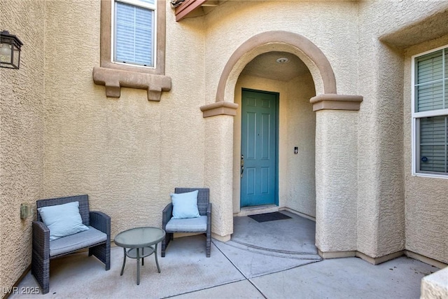 doorway to property featuring a patio area and stucco siding