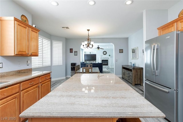 kitchen featuring recessed lighting, a fireplace, a kitchen island, visible vents, and freestanding refrigerator