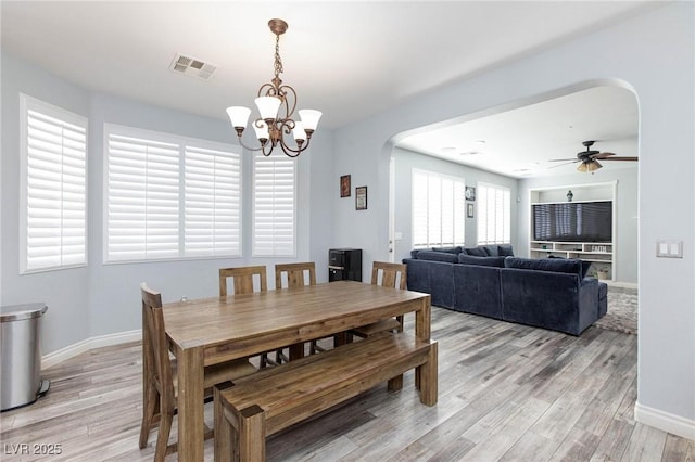 dining room with light wood-style floors, arched walkways, visible vents, and baseboards