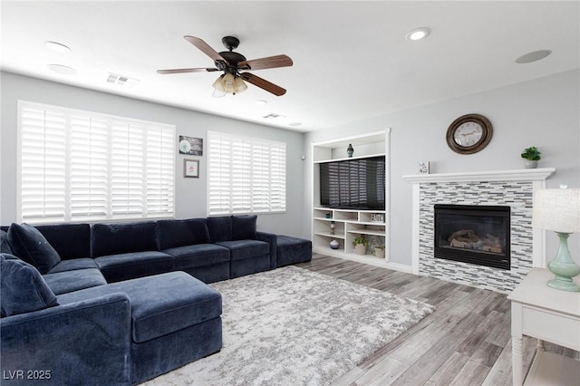 living area featuring visible vents, a ceiling fan, wood finished floors, a fireplace, and recessed lighting