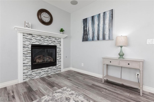 unfurnished living room featuring a fireplace, baseboards, and wood finished floors