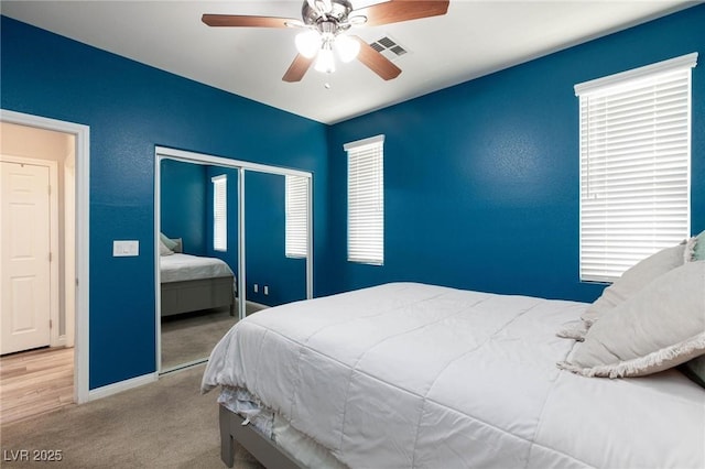 bedroom with baseboards, visible vents, a ceiling fan, carpet floors, and a closet