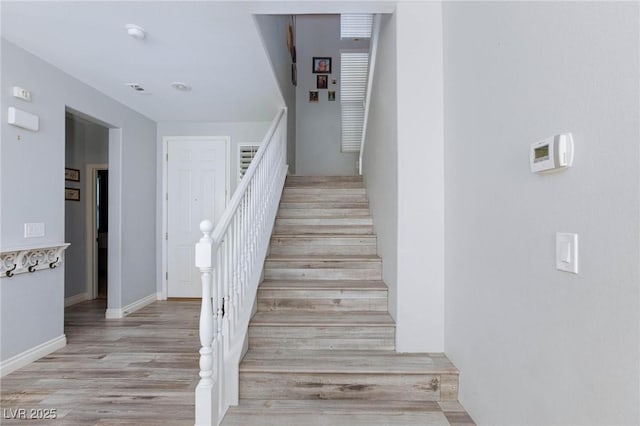 staircase with baseboards and wood finished floors