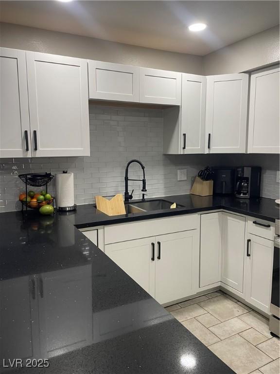 kitchen with a sink, white cabinets, decorative backsplash, and light tile patterned flooring