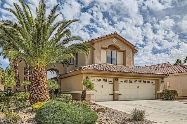 mediterranean / spanish-style home with driveway, a tile roof, and stucco siding