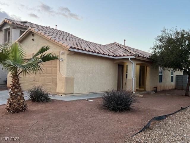 view of front of home featuring an attached garage, stucco siding, and a tiled roof